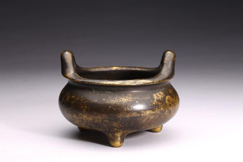A BRONZE TRIPOD CENSER: Qing Dynasty period. Cast with upright handles and base cast with four-character mark Jing Xiang Lin Zhi. H: 4 1/2 in (11.4 cm) D: 5 1/2 in (14.0 cm)