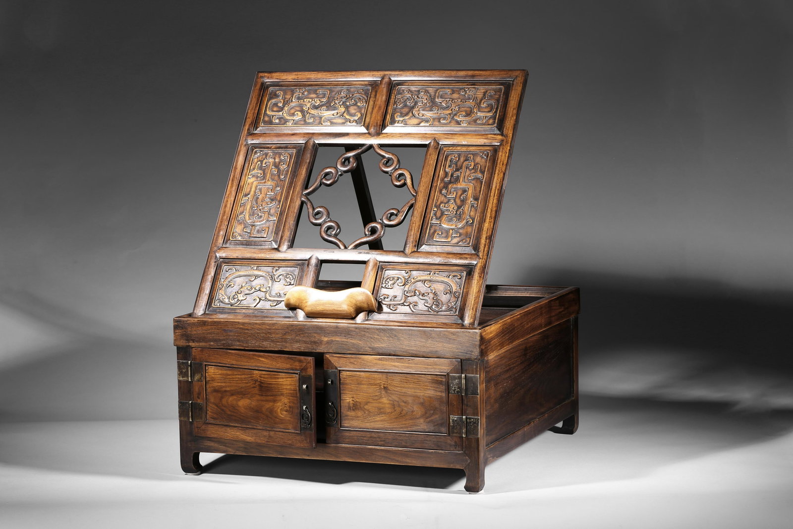 A HUANGHUALI DRESSING CASE WITH MIRROR STAND: Qing Dynasty period. The mirror stand with a rectangular support frame enclosing six rectangular panels,each carved in relief with stylized chilong motif around a central aperture of barbed scroll des