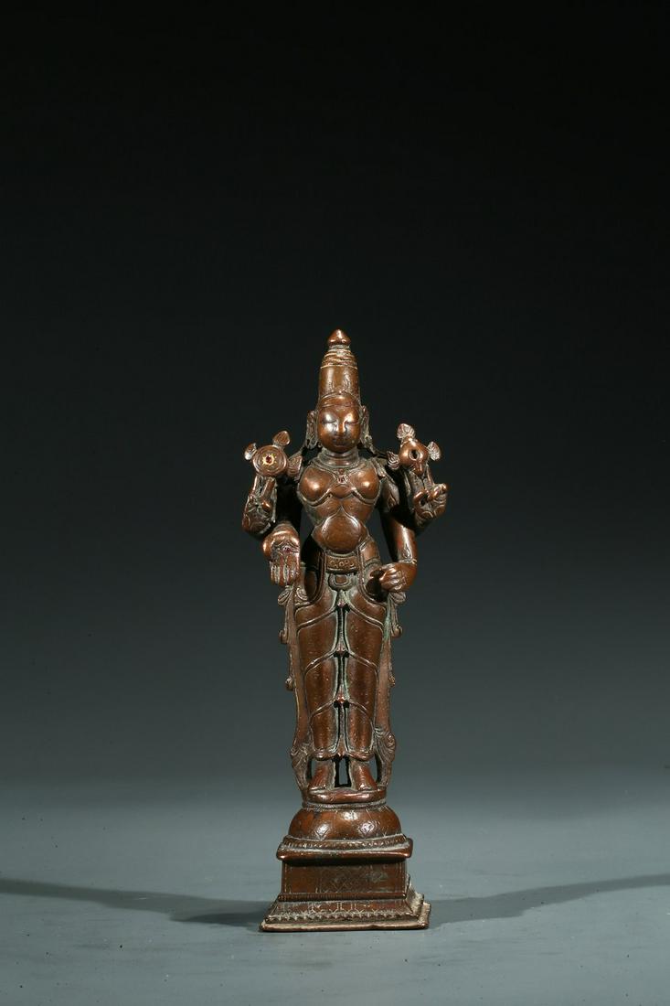 A COPPER ALLOY FIGURE OF STANDING SHIVA: 17th century or earlier. Standing above a square plinth, wearing a dhoti with right hand in mutra, overall adorned with various jewelry, the face serene with gentle smile and elongated eyes surmounted