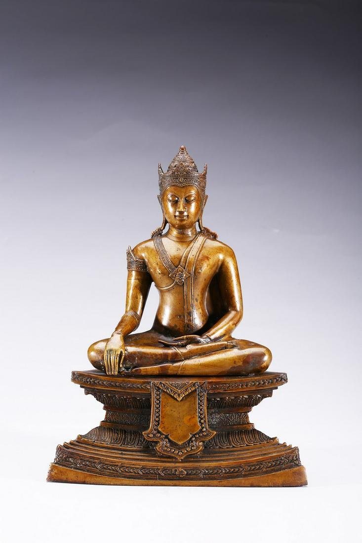 A BRONZE FIGURE OF SEATED BODHISATTVA: The figure is shown seated in dhayanasa on a concave plinth, the hands in bhumisparsha mudra and dhyana mudra, wearing dhoti with incised hem, the face with a serene expression and head framed by an e