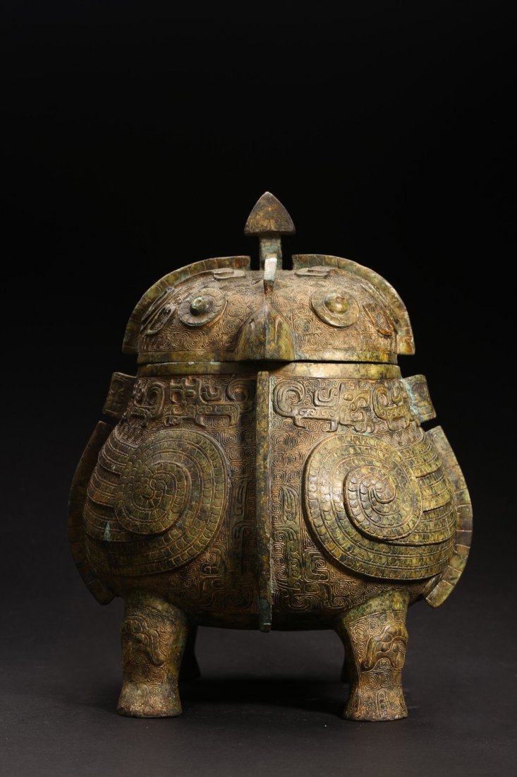 A BRONZE DOUBLE OWL FORM RITUAL FOOD VESSEL: Shang Dynasty period or later. Of oval section in the form of two addorsed owls, their rounded bodies supported on four stout legs, cast in high relief with four wings, the domed fitted cover cast on 