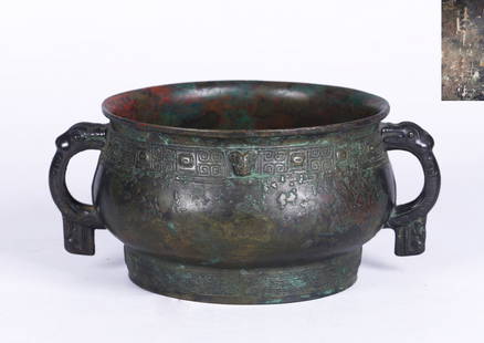 AN ARCHAIC CHINESE BRONZE FOOD VESSEL, GUI: The bowl cast with a band featuring pairs of stylized confronted dragons, each centering on a small raised animal head in high relief, set with a pair of loop handles springing from deer's heads below