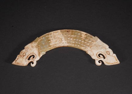 A CHINESE JADE 'DRAGON' HENG PENDANT: The curved pendant is carved with linked c-scrolls on both sides, terminating in dragon-heads on two ends. Western Han dynasty or later. Height: 7/8 in (2.0 cm) Length: 4 5/8 in (11.6 cm) Width: 1/8 i