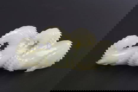 A CHINESE WHITE JADE THREE RAM GROUP: Carved with a single large recumbent ram resting with its hooved legs tucked under its body, flanked at the front and hind with two smaller rams, the stone of a polished even white tone. Qing Dynasty