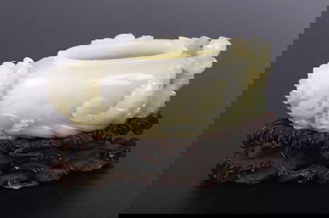 A CHINESE WHITE JADE 'BOY AND DRAGONFISH' WASHER: The washer is modelled in oval form, skillfully hollowed and smoothly polished, the exterior exquisitely carved in high relief with a playful dragonfish clambering up to rest its head and whiskers on