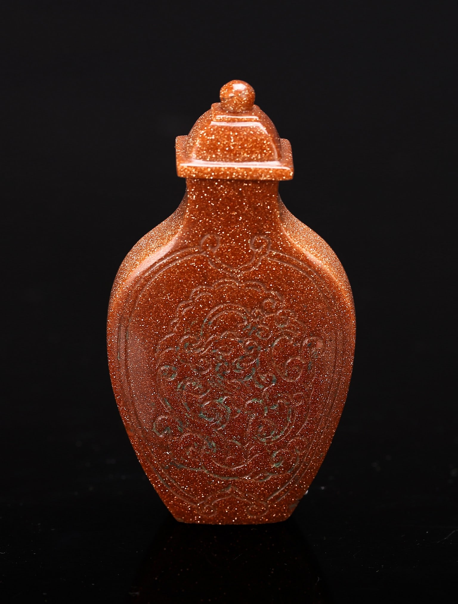 AN AVENTURINE-GLASS SNUFF BOTTLE: 清 金星料器鼻烟壶 The body incised with a stylized sinuous mythical beast on both front and back. Aventurine-glass stopper. Qing Dynasty period. Height: