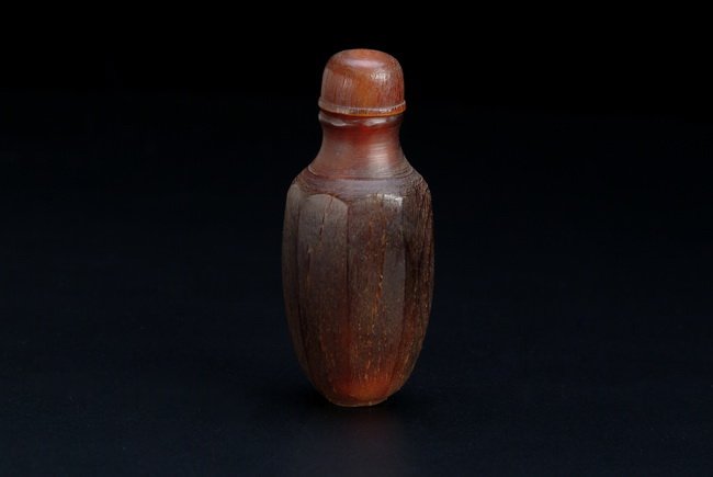 A CHINESE RHINOCEROS HORN CARVED SNUFF BOTTLE: This snuff bottle has a hexagonal shaped insections and tapered into a long neck and mouth, and the base was carved with a well defined short base rim. The piece is equipped with a rhino horn stopper