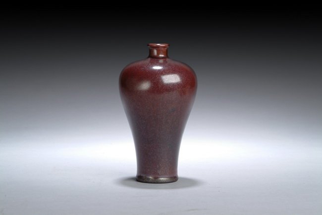 A CHINESE DARK RED GLAZED VASE: This well-glazed dark red vase has a flat base that progressively extrudes into a wide body and wider shoulders. A small thin neck rises from the strong shoulder and forms a slightly bigger opening fo