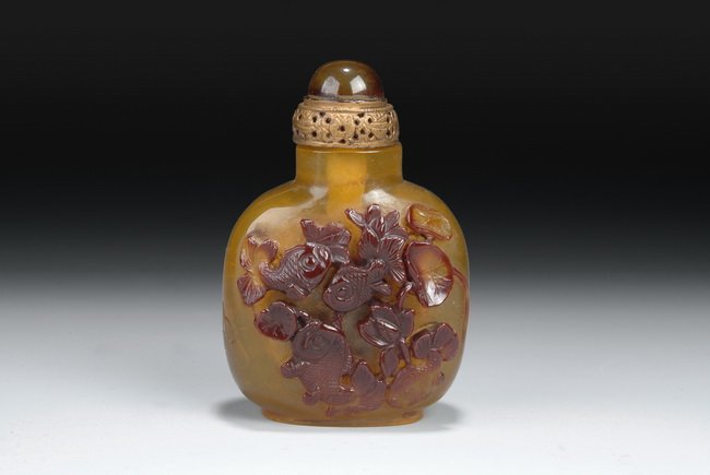 A CHINESE AGATE SNUFF BOTTLE: This well-carved Chinese agate snuff bottle rests on a short foot and expands in a rectangular shape towards the top. Beautiful carvings of black and brown fishes are located on the front and back sid