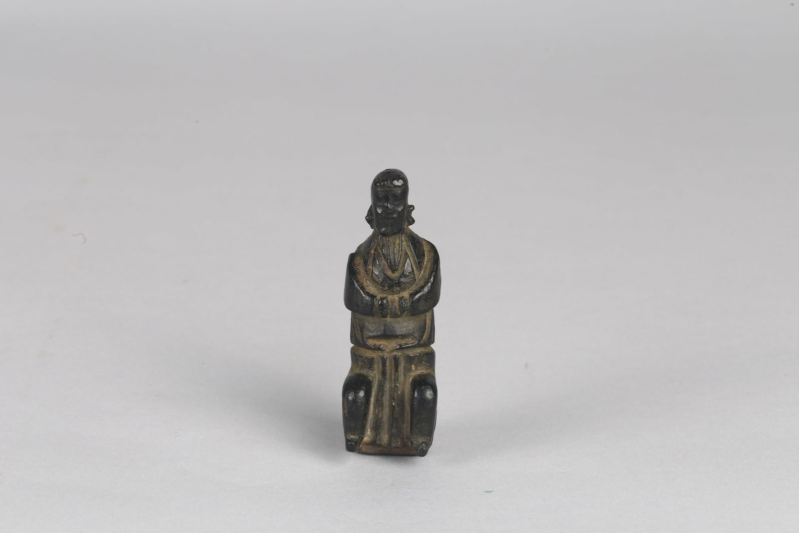A Black Jade or Stone Carved Figure: 年代地區未定 石雕人物 The small figure is carved seated with arms folded across the chest, dressed in long flowing robes. Height: 2 3/4 in (