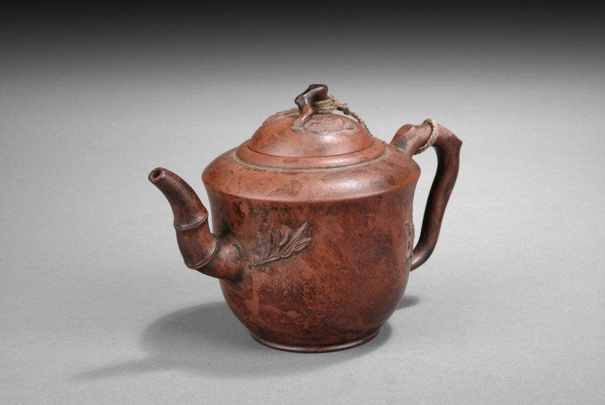A ZISHA STONEWARE TEAPOT: Finely potted and well hollowed, the teapot's body depicts plum tree and orchid, the pouring mouth, handle, and finial depict bamboo, and the lid depicts chrysanthemum, symbolizing Four Gentlemen, or