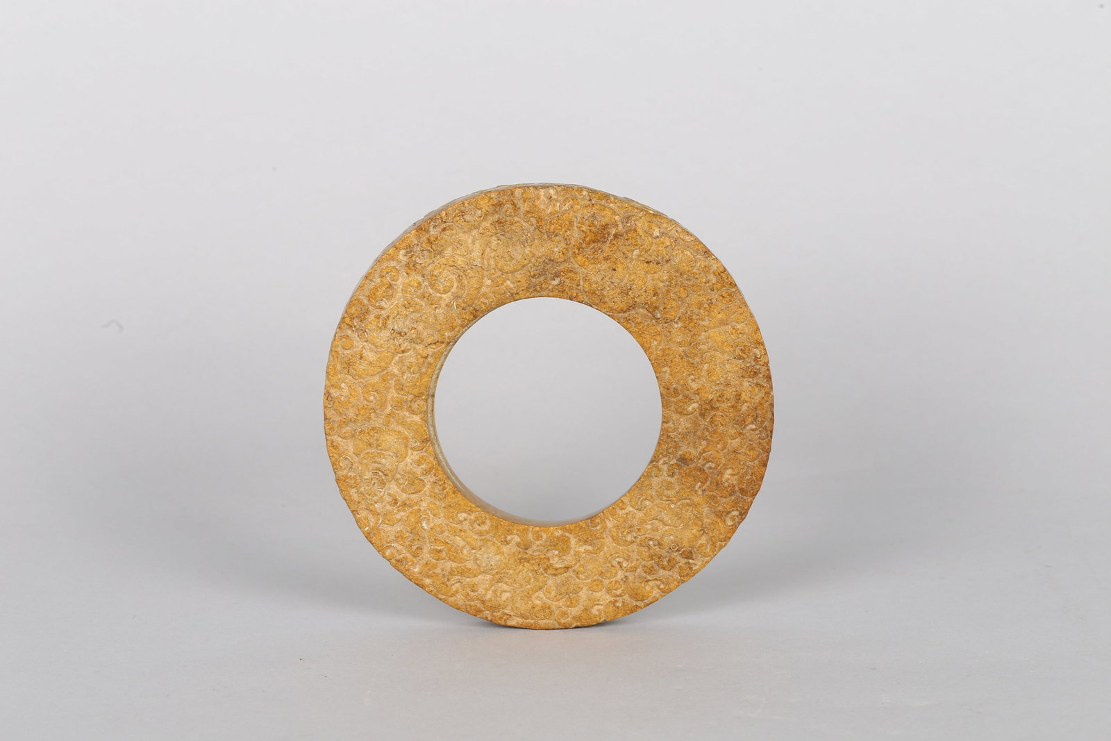 A Chinese Jade 'Mythical Beast' Disc: 六朝 玉獸紋環 The circular disc finely carved in low relief on both sides with dense, interlocking scrolls of archaistic cloud motifs, the stone of pale celadon