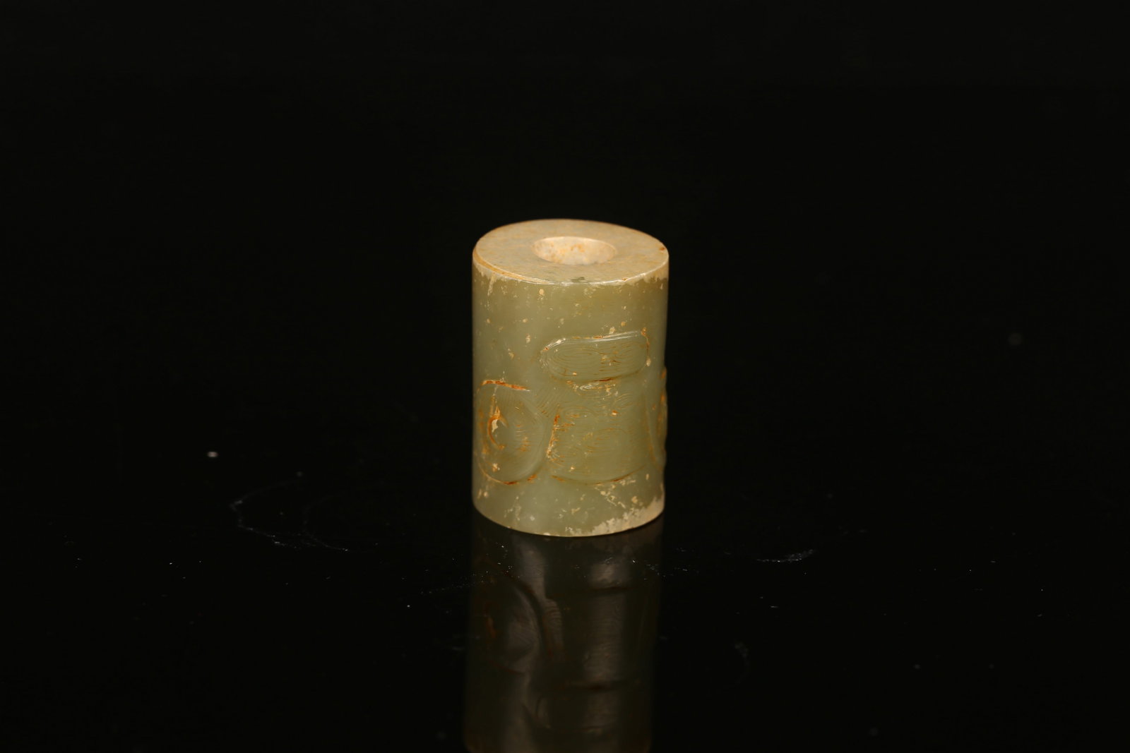 A Small Celadon Jade Cylidner: 良渚 青玉獸面紋勒飾 Of short cylindrical form, delicately incised with stylized taotie mask, the stone is of celadon tone with creamy white