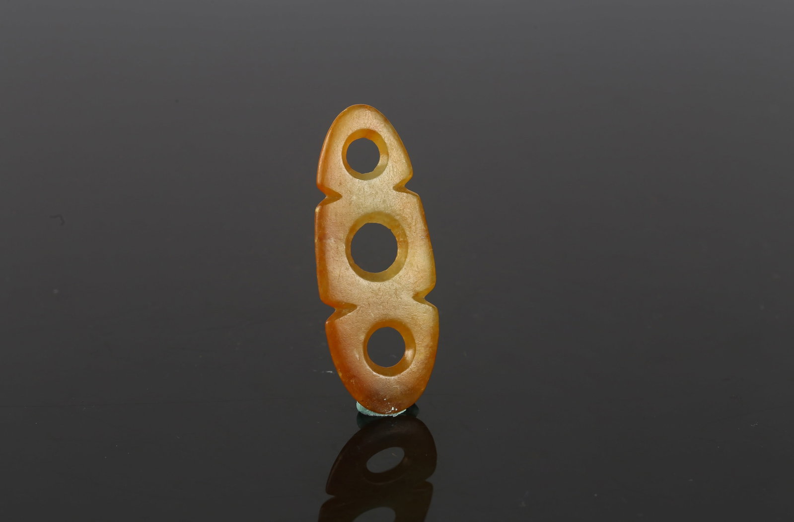 A Jade Three Hole Plaque: 紅山 三孔玉珮 Of elongated form, pierced with three circular apertures, the stone of translucent amber tone with smooth polish. Hongshan Culture. Height:2 in (5.1 c