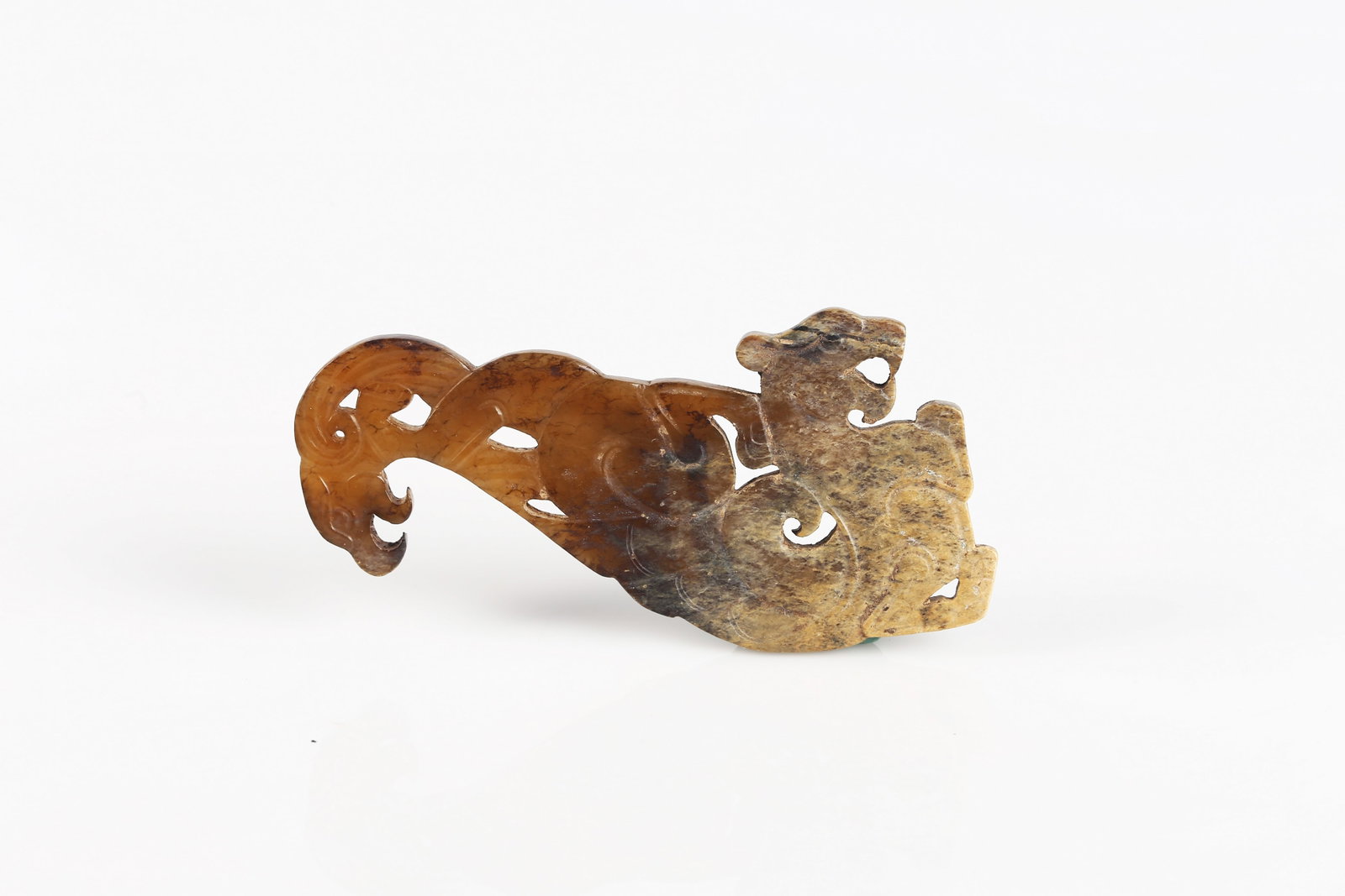 A Jade ‘Mythical Beast’ Pendant: 戰國 或以後 玉獸形佩 The thin plaque carved in openwork as a stylized mythical beast, the body detailed with incised scroll motifs, the stone of