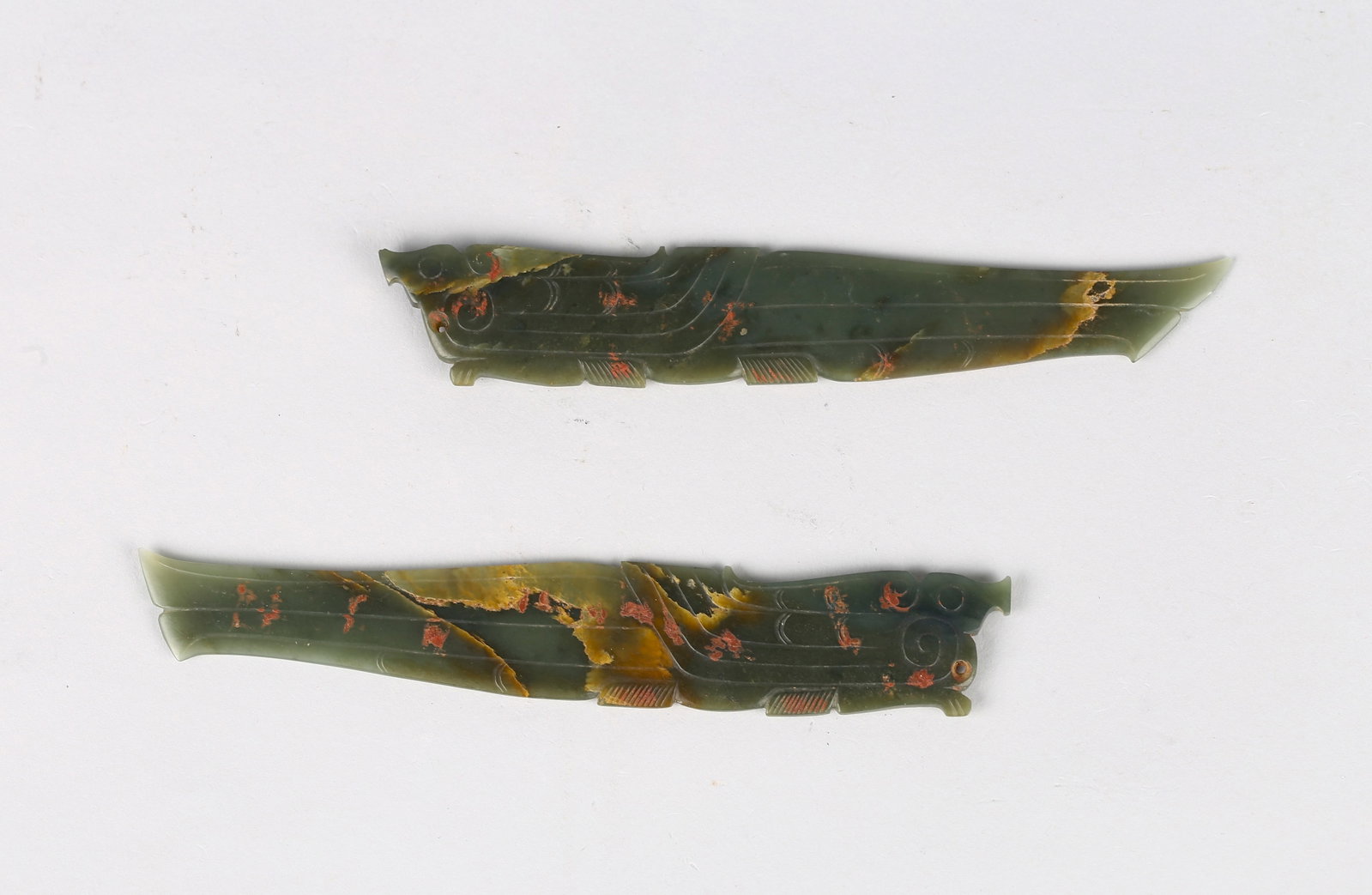 A Pair of Green Jade Phoenix Pendants: 商 青玉鳳凰珮一對 Each slender plaque finely carved in low relief with a stylized phoenix, the elongated body articulated with linear grooves and