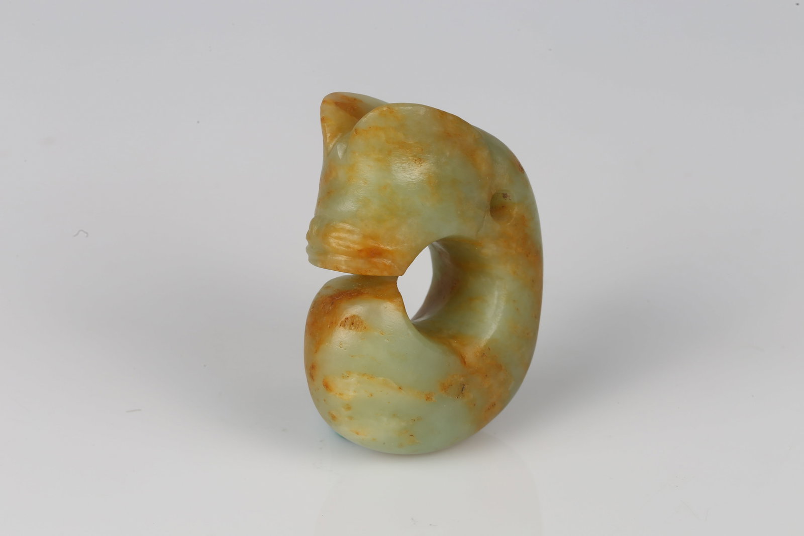 A Celadon Jade Carved Pig Dragon: 紅山 青玉豬龍 Carved in openwork as a stylized sinuous dragon forming a circular body, the head with gently modeled snout and small pierced aperture for