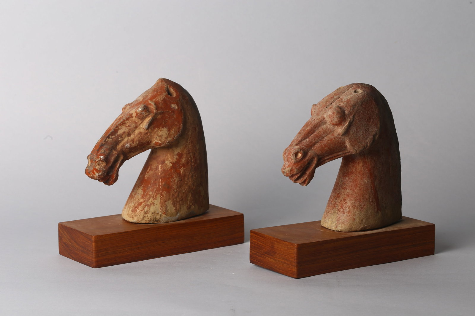 A Pair of Painted Pottery Horse Heads: 漢 陶胎彩繪馬首像一對 Each modelled with elongated neck and gently bowed head, the features rendered with alert ears and defined muzzle, the