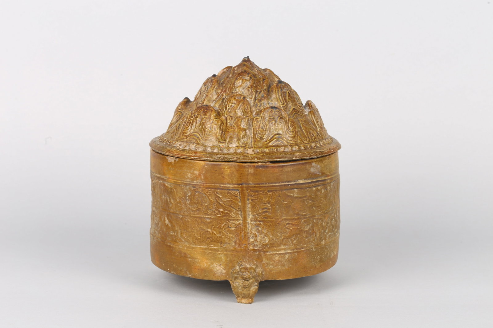 A Chinese Olive Glazed Pottery 'Boshan' Censer: 漢 綠釉博山蓋神獸紋樽 The cylindrical body raised on three short feet and encircled with bands of molded mythical beasts, covered overall