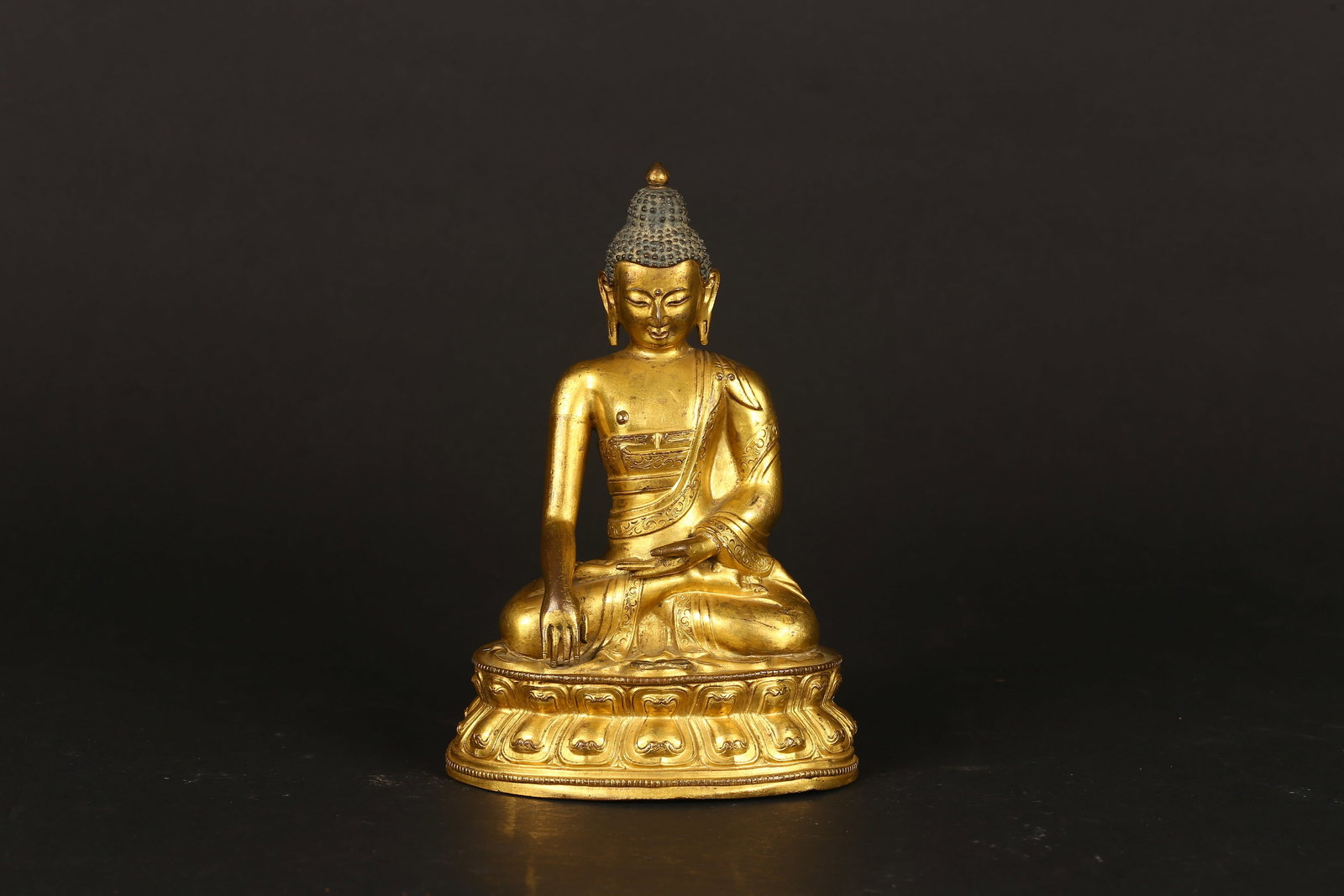 A Gilt Bronze Figure of Shakyamuni: 清中期 銅鎏金釋迦摩尼坐像 The buddha is shown seated in vajrasana on a lotus base with his right hand in bhumisparshamudra while