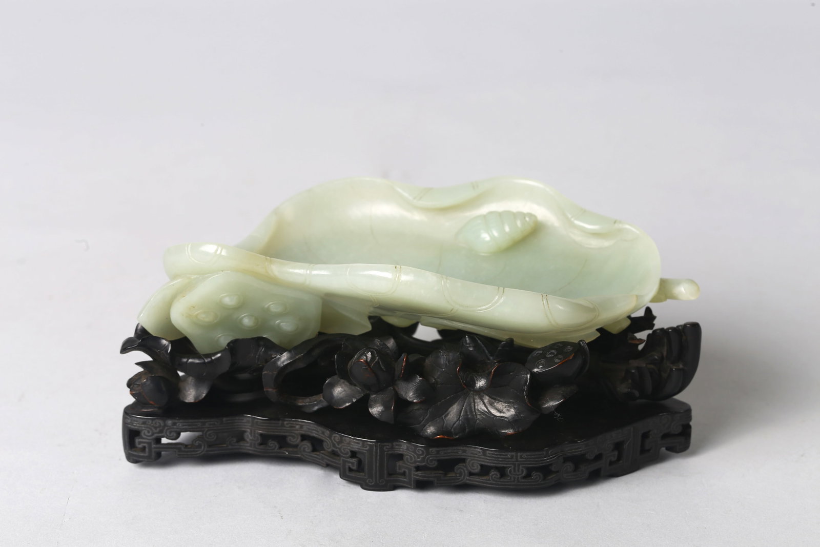 A Fine White Jade 'Lotus' Washer and Zitan Stand: 清中期 白玉荷葉海螺洗 紫檀嵌銀線木座 The vessel naturalistically carved as a large, furled lotus l