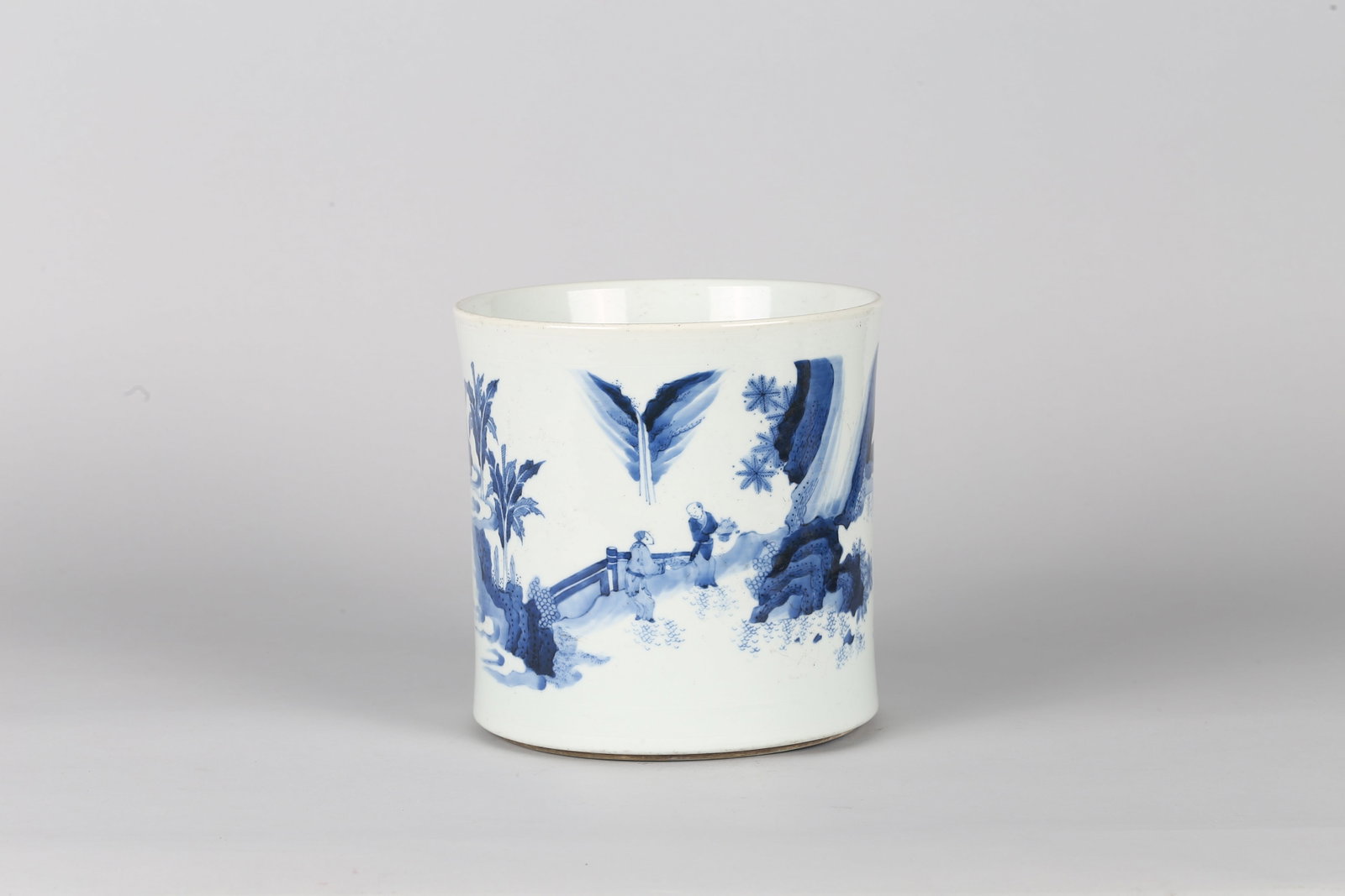 A Chinese Blue and White 'Figures' Brushpot: 清 青花人物故事圖筆筒 Of cylindrical form, painted in underglaze blue with a continuous landscape scene of figures in a garden setting among