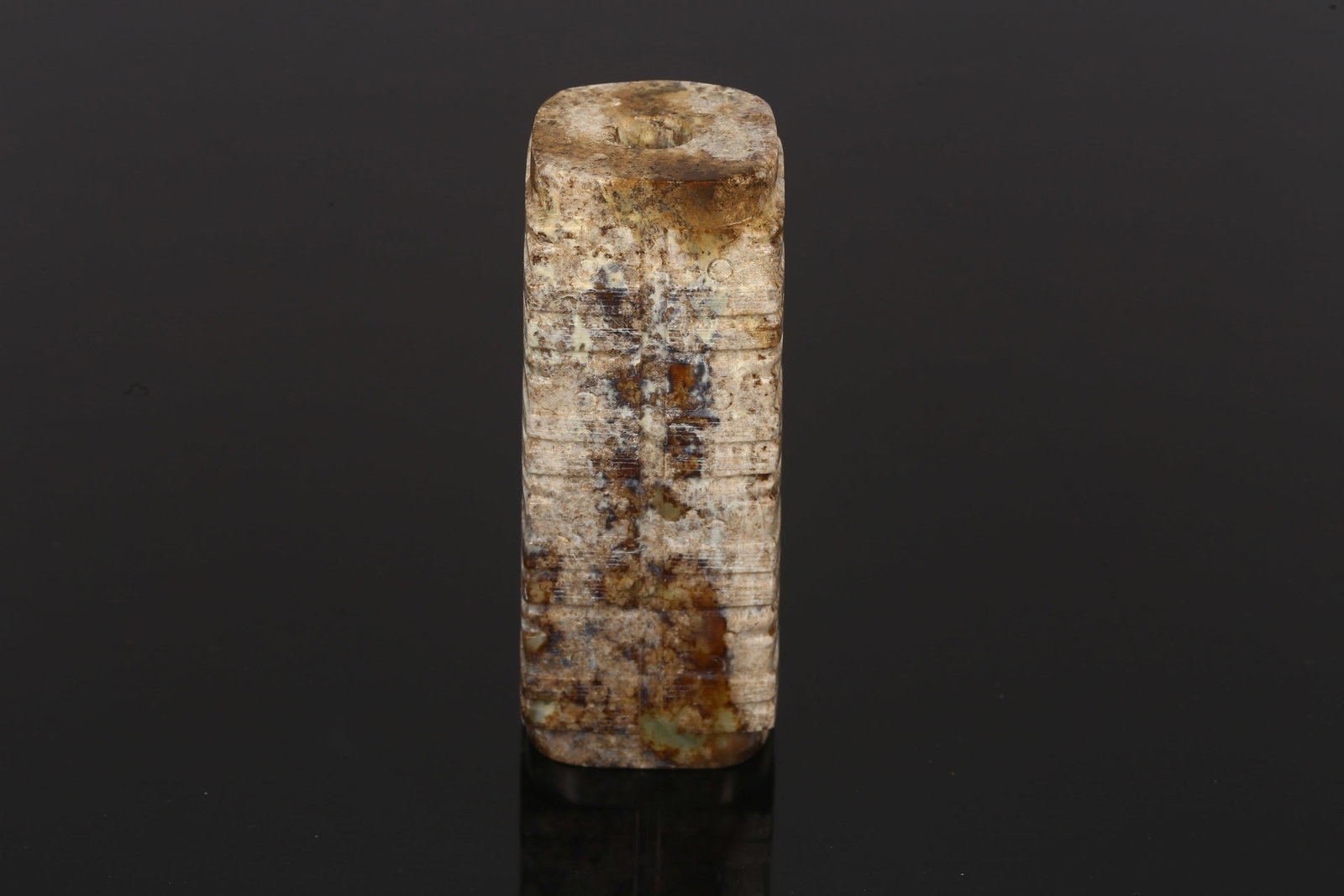 A Small Jade Carved Cong: 明 玉琮 Of rectangular section with softly rounded edges, pierced with a central tubular aperture, the sides subtly incised with faint horizontal bands, the stone of mottled