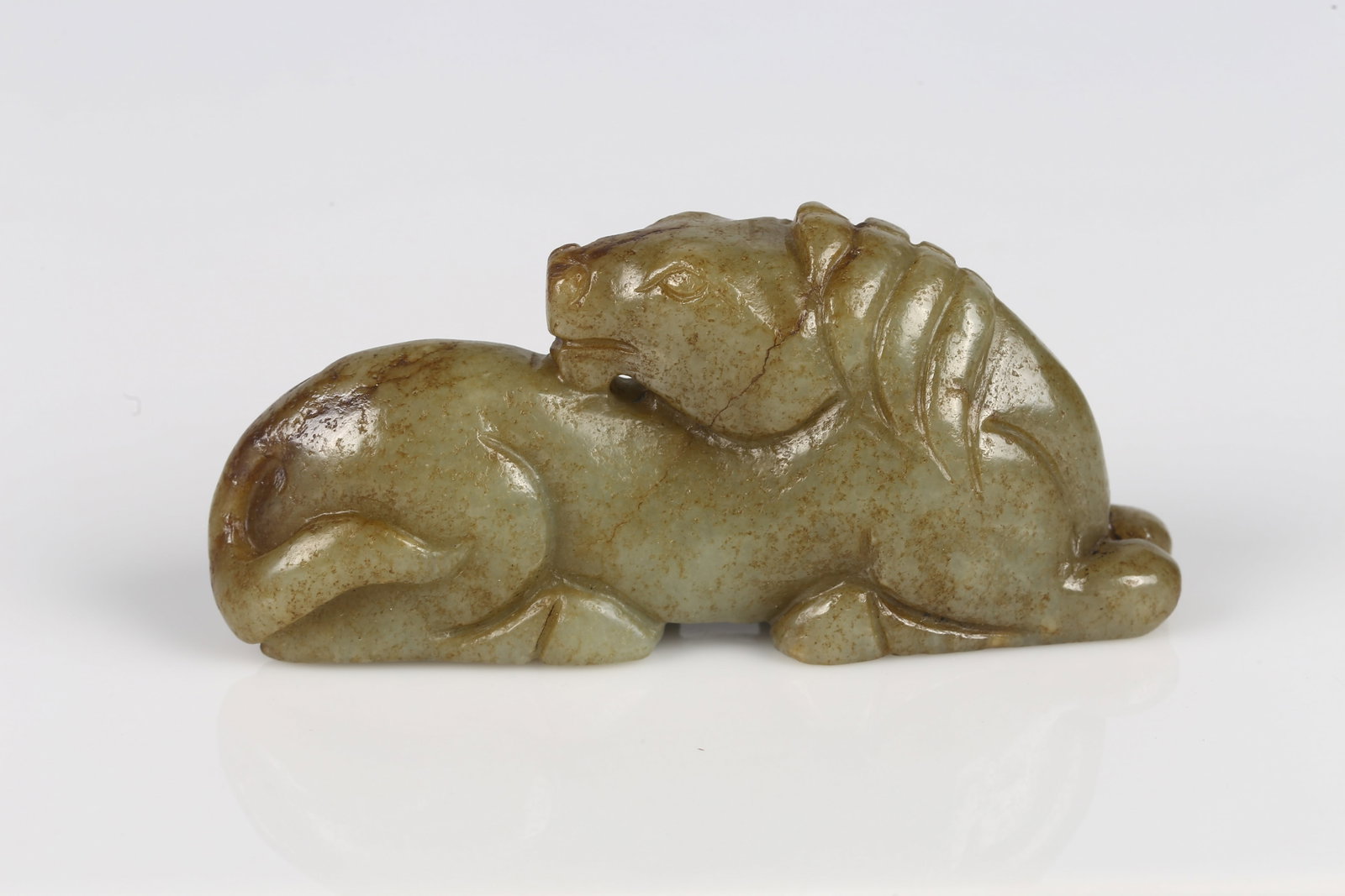 A Small Jade Carved Horse: 明 玉馬把件 Of a recumbent horse, the smoothly polished body rendered with tucked legs and a gently raised head, the stone of even tone with light russet inclusions. Ming