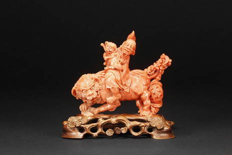 A CORAL CARVED FIGURAL GROUP OF ELDER AND LION: The figural group depicts an elder riding on a prowling lion, while carrying a small Qilin in his hands, carrying a horsehair whisk on the back, and dressed in loose robe, the tail of large lion carri