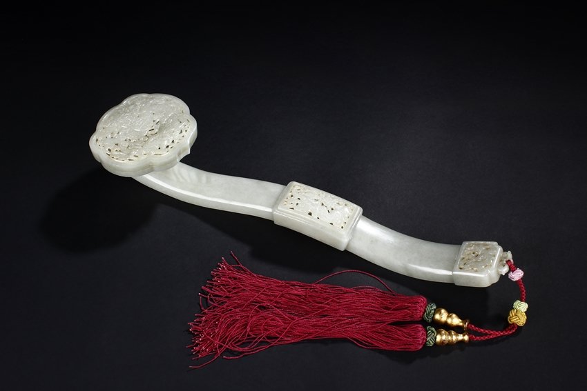 A PIERCE CARVED WHITE JADE "DRAGON" RUYI SCEPTER: The ruyi head pierce carved with a five-clawed dragon flying amidst clouds, the reverse pierce carved with coin pattern, a rectangular block pierce carved with mythical beast rests on the peak of arch