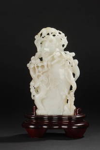 A CARVED WHITE JADE 'MONKEYS AND PEACH' VASE: The vase is of flattened baluster form with elegantly gnarled peach branches rising from the base. Intricately carved and pierced in open work relief, its blossoming branches extending upwards around