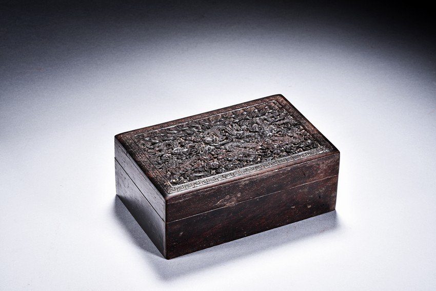 A ZITAN CARVED DRAGON BOX: The box is of rectangular shape, the surface vividly carved in relief with cloud and dragon motif. L: 6 1/4 in (16 cm)