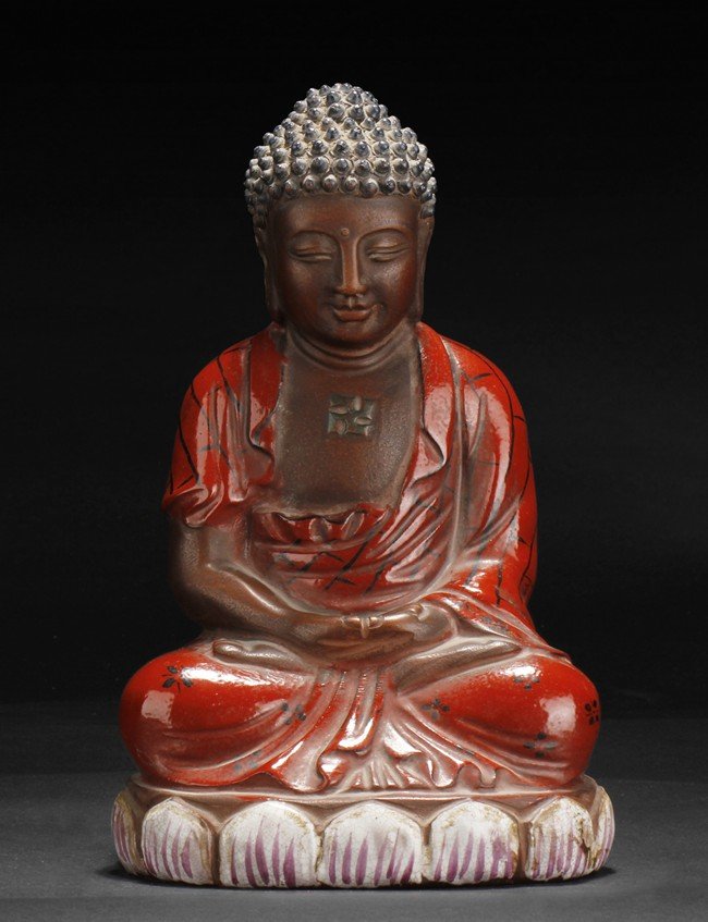 A PAINTED AND GLAZED ZISHA SHAKYAMUNI FIGURE: Seated in dhyanasana on top of lotus throne, both hands in dhyanamudra, dressed in loose red drape exposing chest with swastika symbol, the face with a smiling and serene expression with eyes closed, 