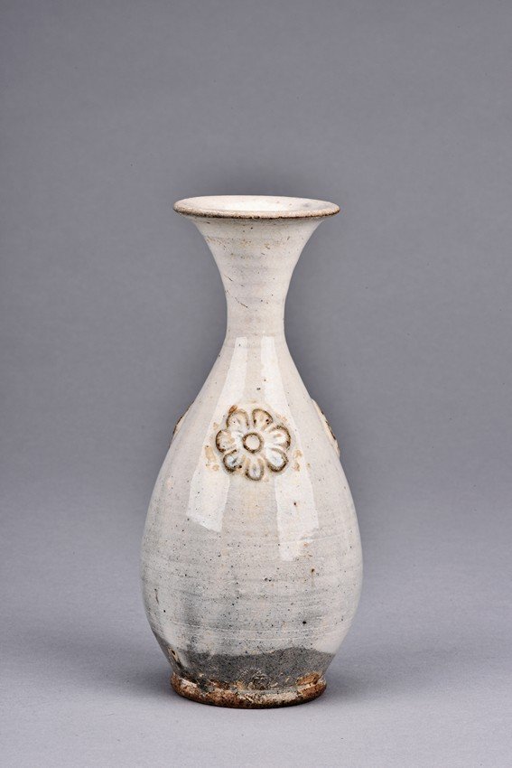 A WHITE GLAZED 'FLOWER' VASE: Overall glazed in white, the bottom unglazed, the waisted neck rising to flared rim, the upper body potted with flower decoration in relief. Height: 7 1/4 in (18.5 cm)