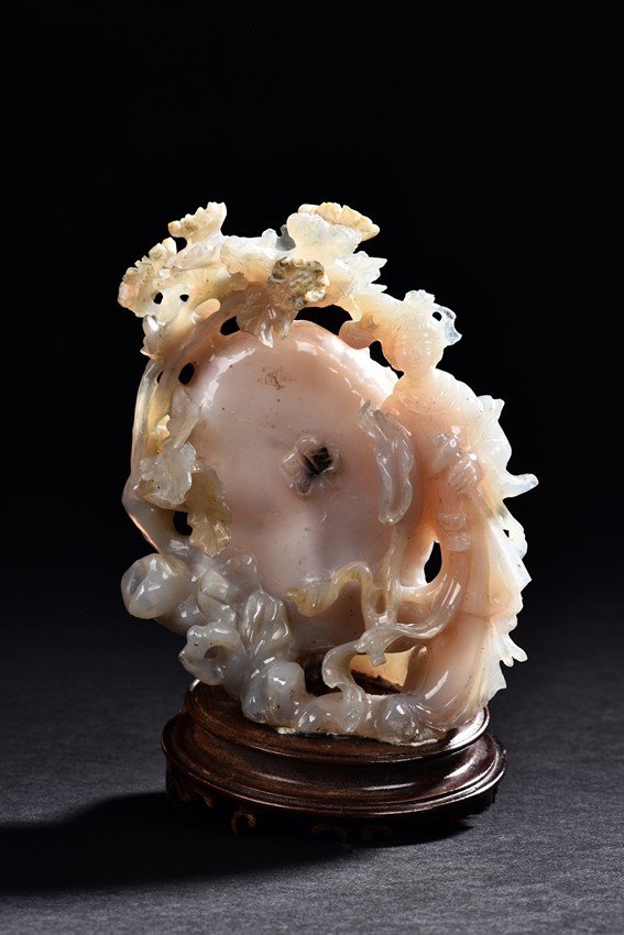 A JADE CARVING OF BEAUTY: Carved with a slender beauty wearing long and flowing robe by a large and oblong shaped rockwork and flowers growing along the side. Height: 6 in (15.5 cm)