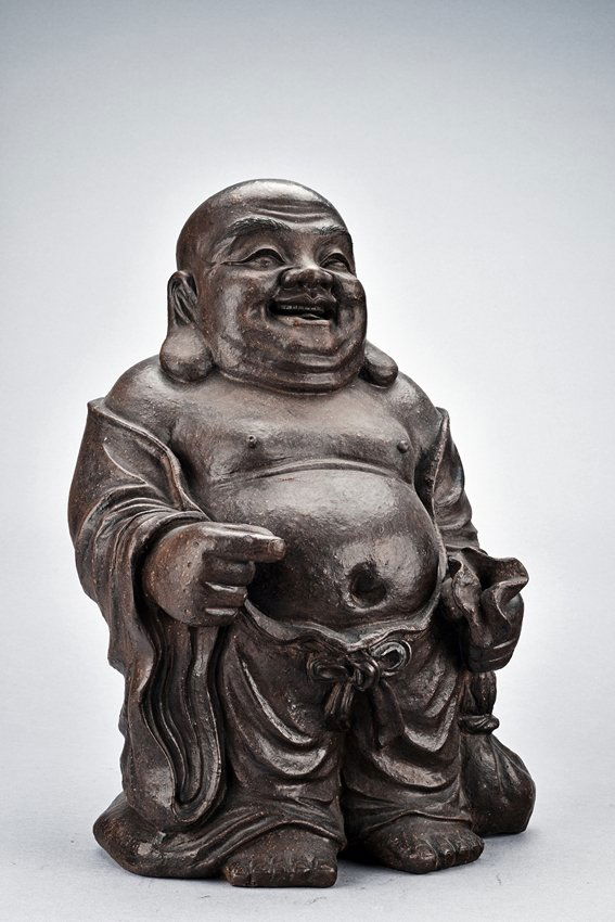 A YIXING ZISHA FIGURE OF BUDAI: The figure is shown wearing long flowing robe, the large belly exposed, left hand dragging a bag, the face with laughing expression flanked by two large and pendulous earlobes. Qing Dynasty period. He