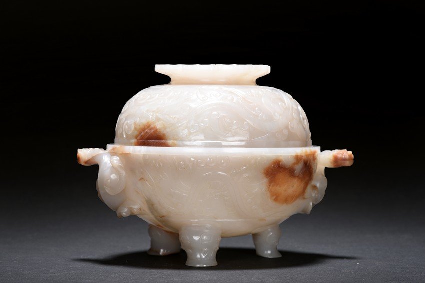 AN AGATE 'MYTHICAL BEAST' CENSER WITH COVER: The tripod censer is supported on three mythical beast feet, both sides carved with twisting chilong in high relief, the exterior with scrolled dragon motif. Qing Dynasty period. Height: 4 1/4 in (10.