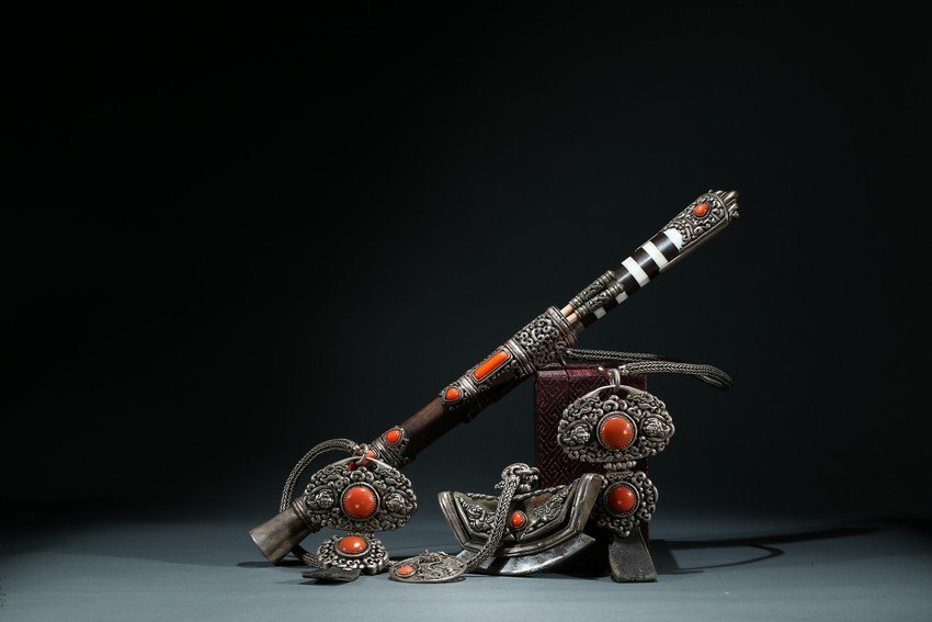 A SET OF TIBETAN SILVER CORAL INLAID UTENSILS: Consisting of a knife set with silver mounted case, containing a pair of bone chopsticks and knife, the silver sheath and toggles reticulated with scrolled design and inlaid with large coral beads. La