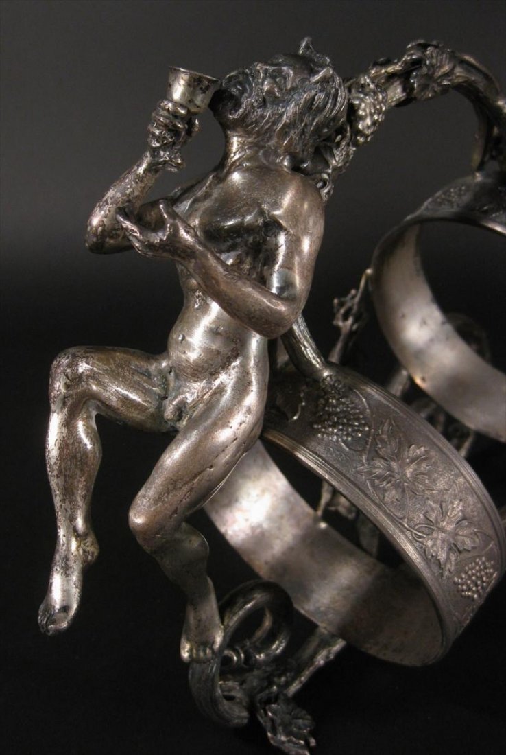 PAIR OF STERLING FIGURAL WINE CADDYS BACCHUS: PAIR OF Sterling Silver FIGURAL WINE BOTTLE CADDYS ONE WITH BACCHUS FIGURE & THE OTHER WITH NUDE WOMAN FIGURE WITH BARREL by Camusso, Lima Peru, MEASURING 13 & 1/2 INCHES IN LENGTH & WEIGHING 61 TROY 