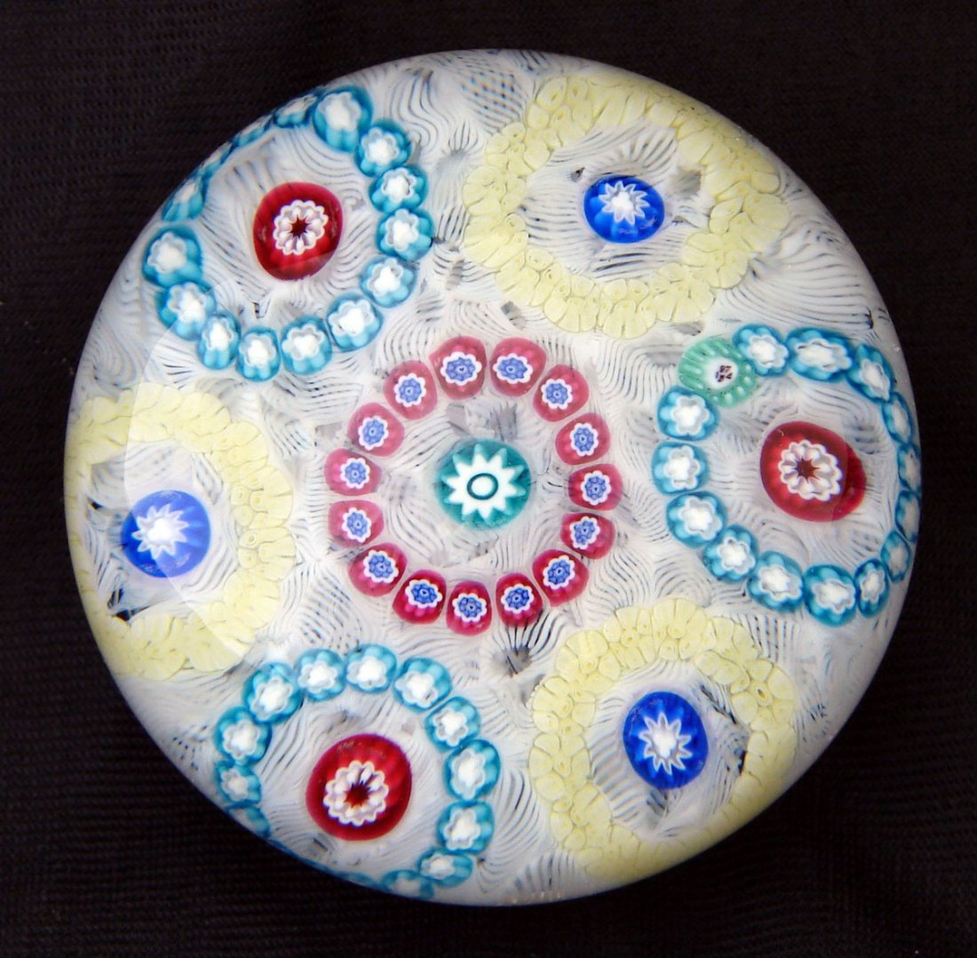 1974 Modern Baccarat Paperweight Millefiore: Baccarat Modern 1974 with "B 1974" cane. Six rings of millefiore in red and pastel colors on a bed of white scrambled latticinio, three-fourths globe shaped. This is 3 inches diameter.