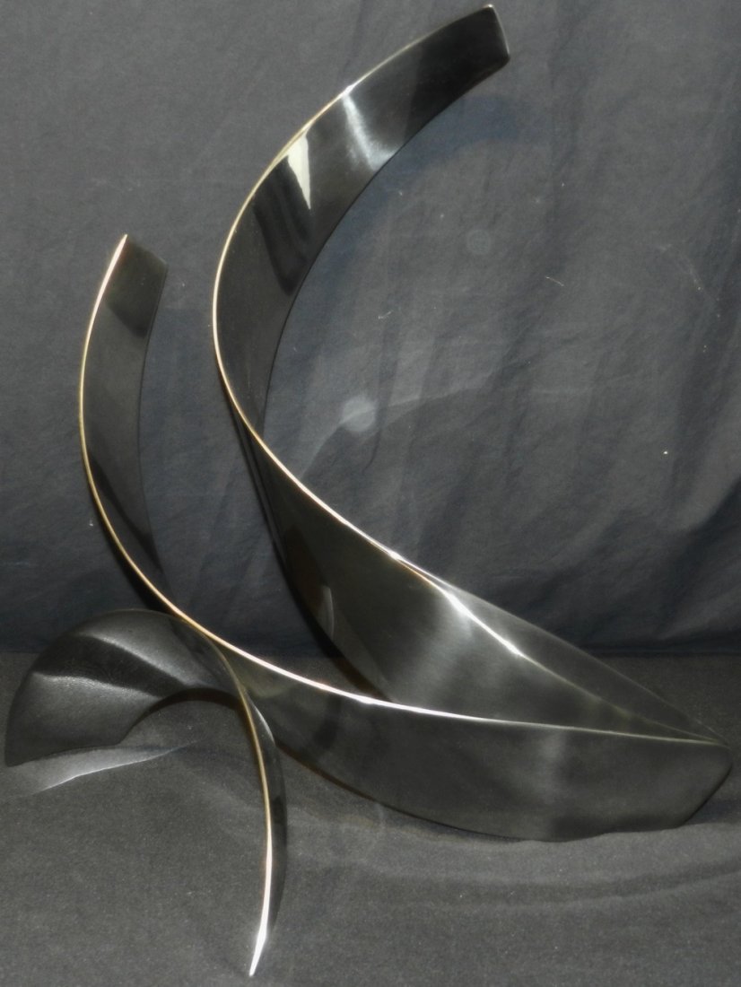 "Thrust" Stainless Steel Sculpture by Jack Arnold: Stainless steel sculpture titled "Thrust" by Jack Arnold (American, 20th Century). This sculpture features ribbons of steel that stand 21" high.