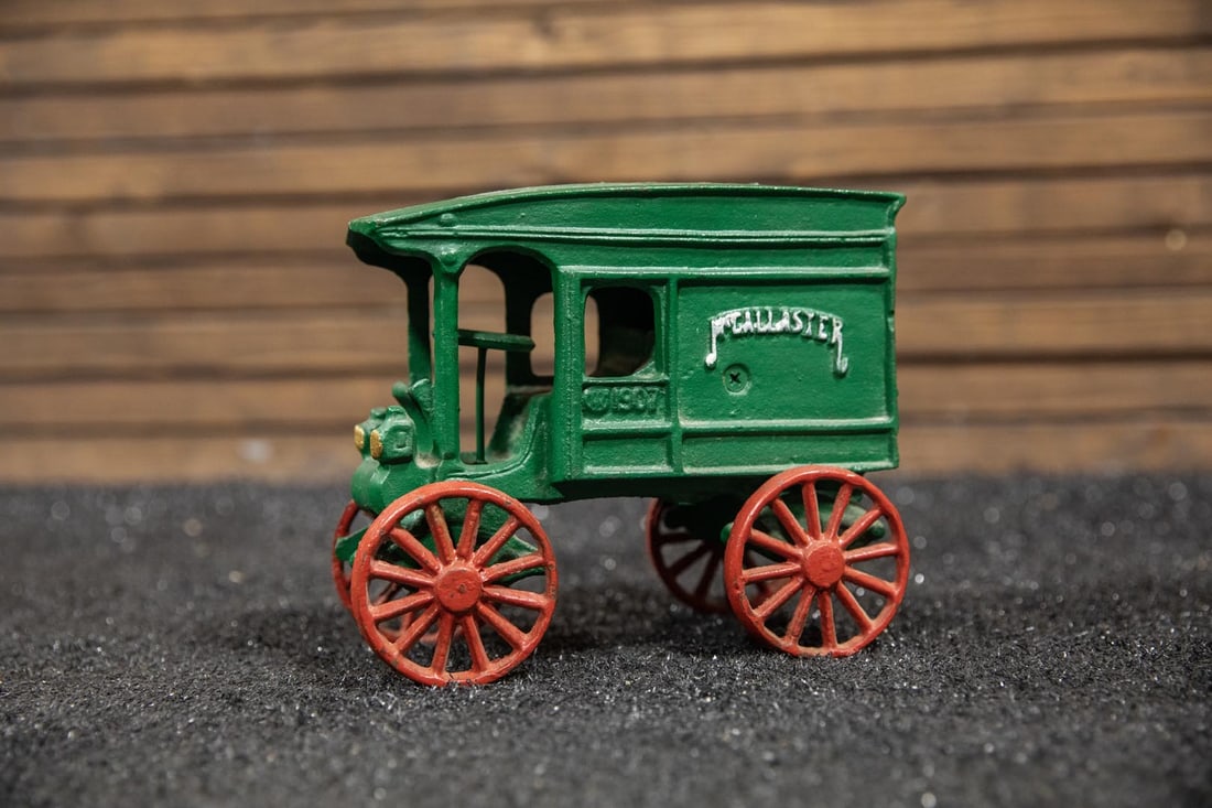 1907 Autocar Cast Iron Toy: Heavy cast iron reproduction of an early motorized truck, "McAllistar" embossed on the signs, painted green with red spoke wheels.