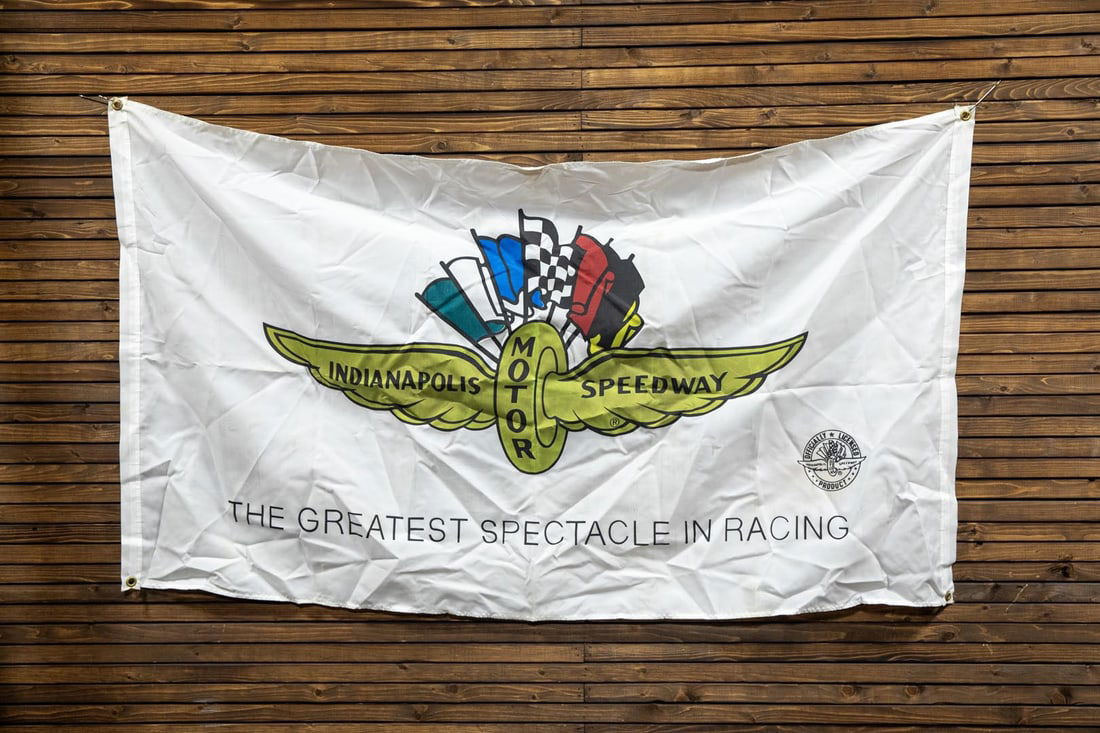 Indianapolis Motor Speedway Banner: Presentation of Indianapolis Motor Speedway's iconic flag topped with winged wheel design promoting the Greatest Spectacle in Racing, officially licensed product, age unknown. 
