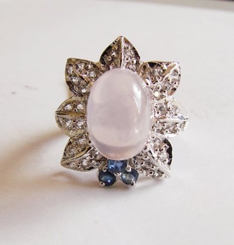 Rose Quartz-W/ Topaz-Saph Ring 10.07Ct 18kW/g Over: Gem Type: Natural Rose Quartz, White Topaz and Sapphire Item: Ring Rose Quartz Weight:8.15 Carat Cabochon Oval Measurement: 13.3x9.5x8.5mm Clarity: Transparent/Translucent, Color: Pink, Treatment: Non