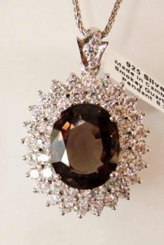 Smoky,Creation Diamond Pendant 9.41Ct 18k W/g Overlay: Gem Type: Natural Smokey Topaz/Creation Diamond Smoky Topaz:5.45 Carat Oval Shaped, Cut: Facet Size:14.5x11.8x7mm Clarity: VS1, Color: Dark Brown, Treatment: None Hardness 7 Origin, Brazil 44 Pieces C