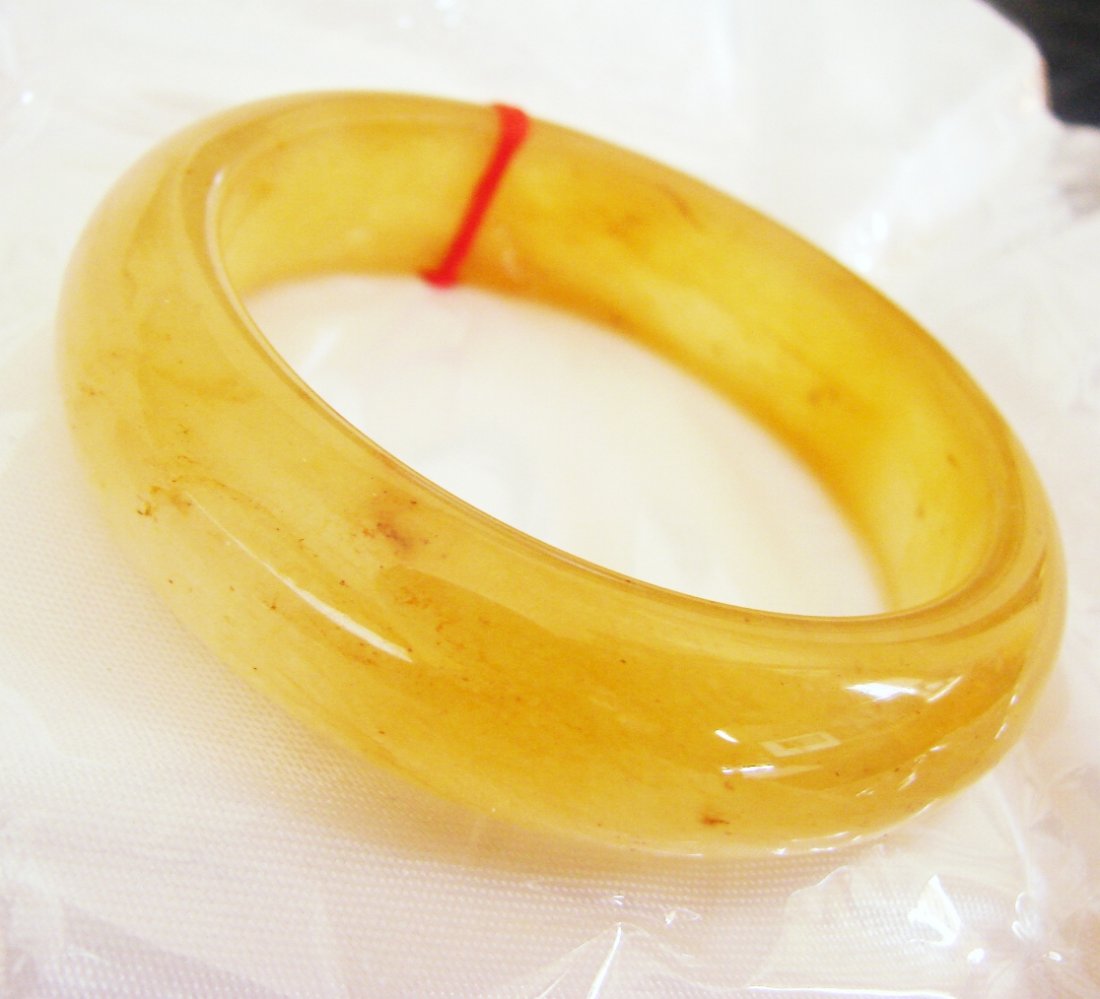 Natural Jadeite Jade Bangle JBA-2B SZ: 7: Natural Jadeite Jade Bangle Clarity: JBA-2B, Color: Golden and styli Orange Transparency: Semi -Transparent Shape & Cut: Solid Jade Band Haft Round Jade Finish: High Polish Remarks: Genuine Jadeite Qu