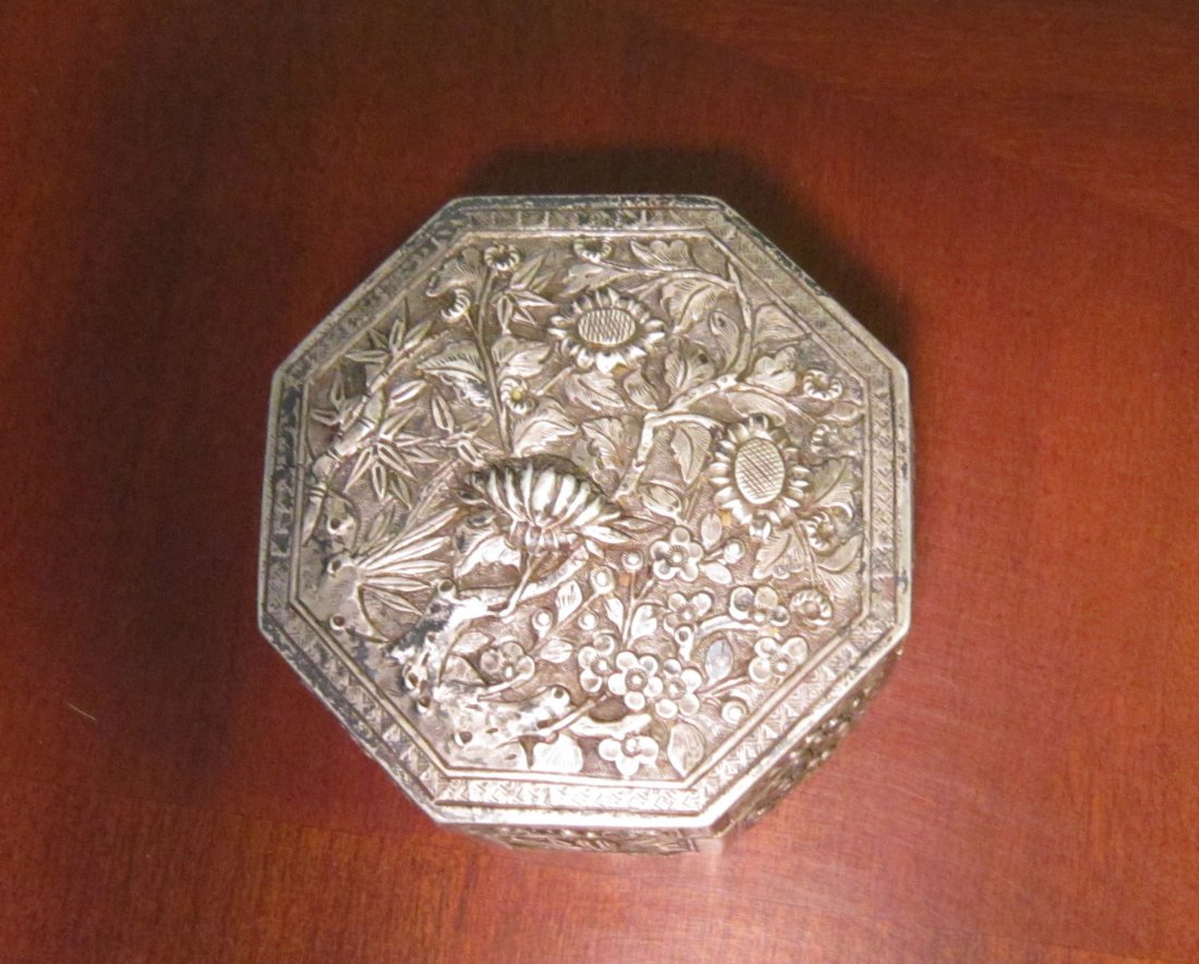 A Small Chinese Silver Octagonal Pill Box: A Small Antique Chinese Silver Octagonal Pill Box with Raised Flowers, including Prunus, bamboo, chrysanthemums and other, fine work, maker's mark. Circa 19th/20th Century, D2.5" (6.2cm).