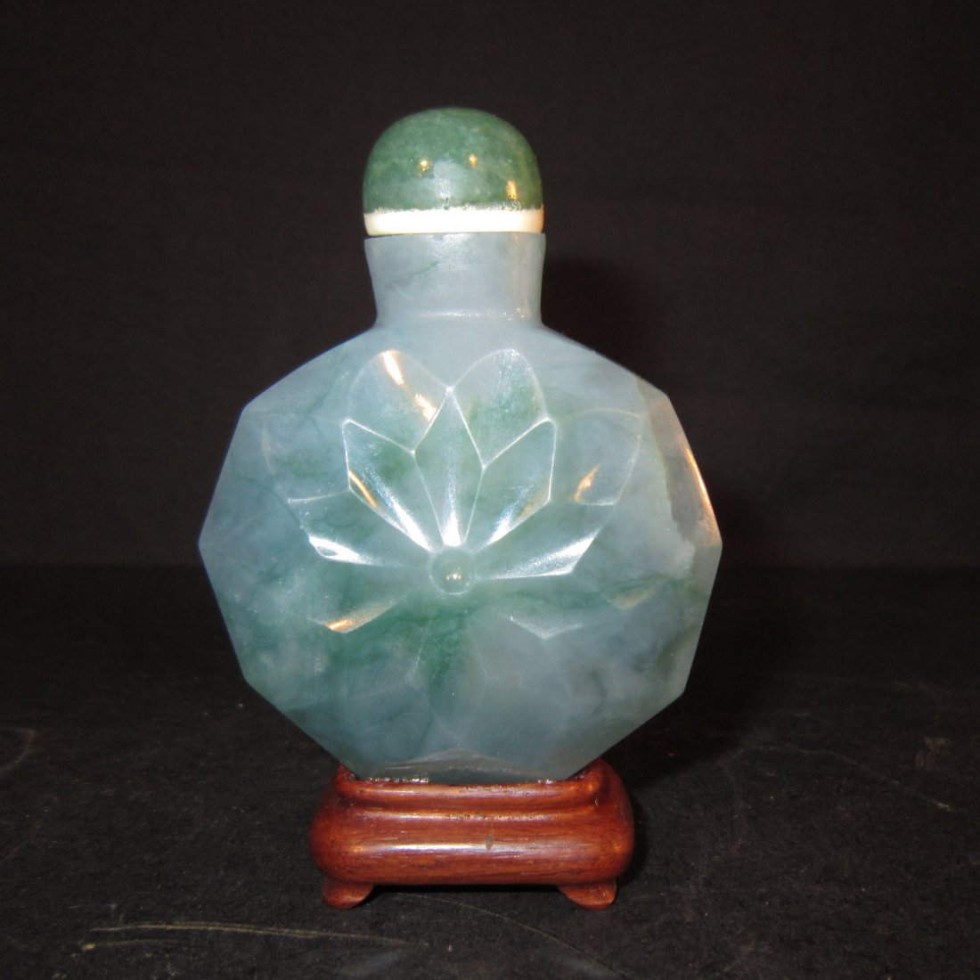 A Chinese Jadeite Snuff Bottle: Circa late Qing Dynasty - Republic period, Of octagonal faceted form with a large carved central flower on both sides, the stone a light moss green color with some veins of rich green, ivory spoon and