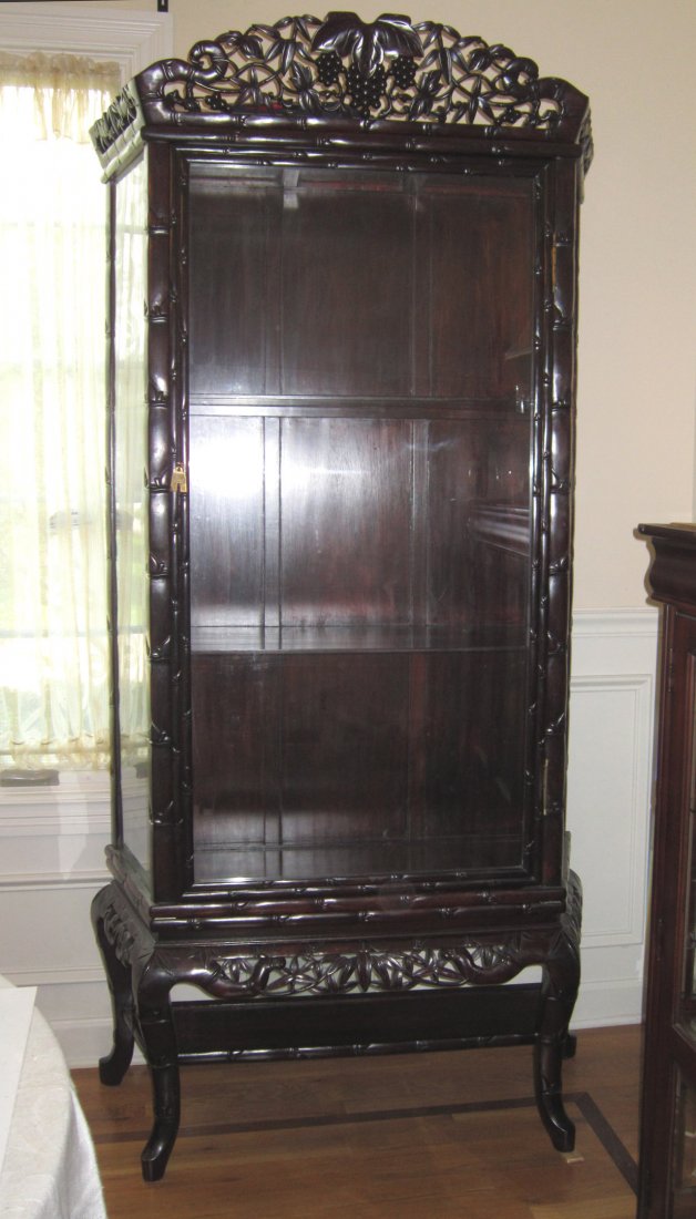 A Chinese Rosewood Display Cabinet on Stand: Circa late 19th – Early 20th Century, reticulate carved Rosewood (Hongmu 红木) in grape and bamboo design, hinged front glass panel door; 3 layers with two Rosewood shelves, rosewood sta