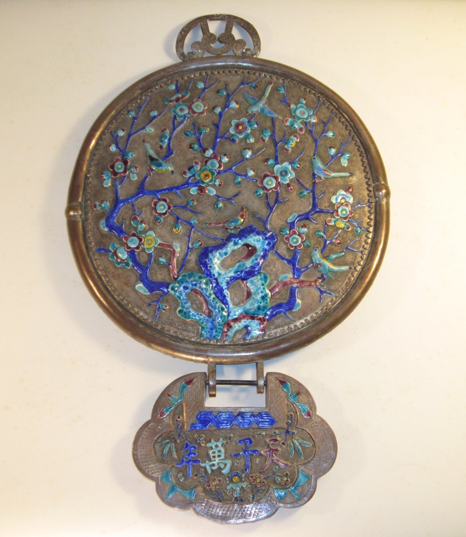 A Chinese Silvered and Enameled Table Mirror: circa late Qing dynasty/Republic period, , enameled with birds and flower, silver gilt over bronze base, a butterfly-inspired hook attached to bottom, 15 in. (38 cm) long